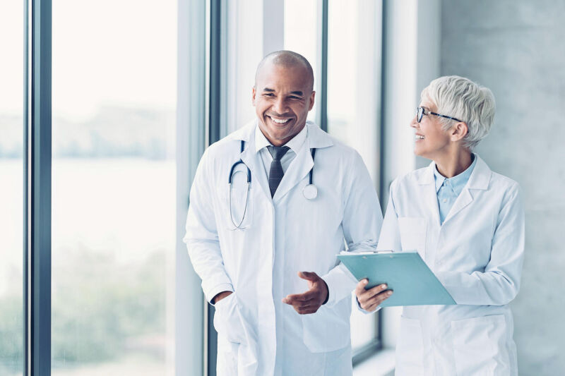 Two doctors walking side by side and discussing a NRCME exam Two doctors walking side by side and discussing a NRCME exam